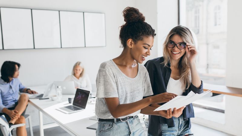 Zwei Frauen im Vordergrund stehend - zwei Frauen im Hintergrund sitzend