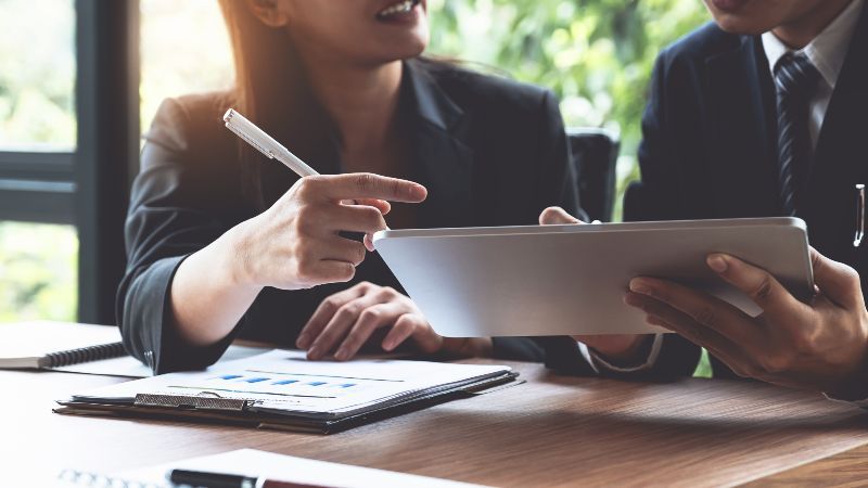 Frau mit Schreibstift und Mann mit Tabletcomputer im Gespräch