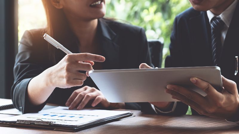 Frau mit Schreibstift und Mann mit Tabletcomputer im Gespräch