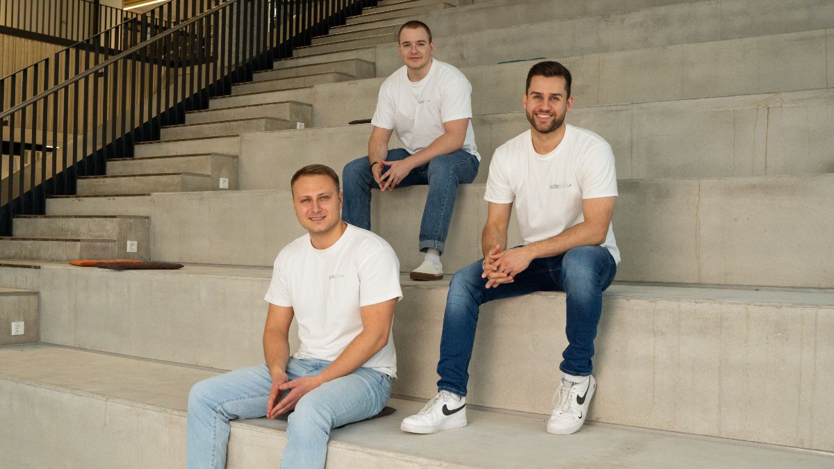 Drei junge Männer sitzen auf Treppenstufen und blicken in die Kamera